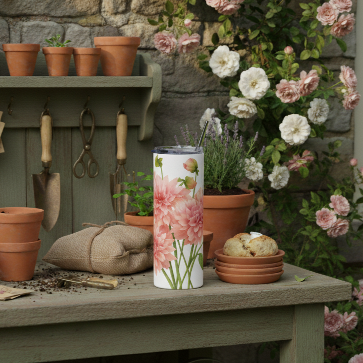 Tumbler with floral design on a table surrounded by potted plants and gardening tools.